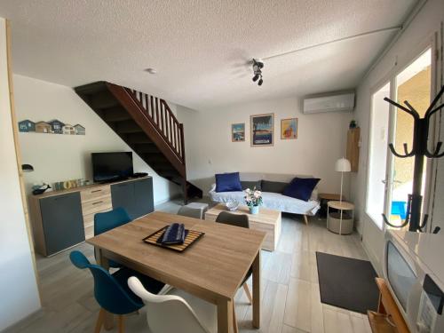 a living room with a wooden table and a dining room at Charmante maison à Le Barcarès in Le Barcarès