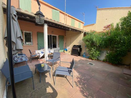 a patio with chairs and a table and a grill at Charmante maison à Le Barcarès in Le Barcarès