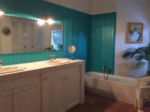 une salle de bain avec deux lavabos, une baignoire et un miroir dans l'établissement La maison Danna, à Lauris