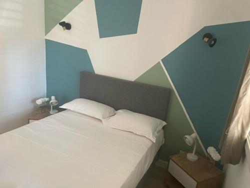 a bedroom with a white bed and blue and white walls at Corse du sud Fiori di cala rossa T2 rez de jardin dans résidence piscine in Lecci