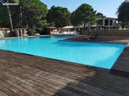 une grande piscine bleue avec une terrasse en bois dans l'établissement Corse du sud Fiori di cala rossa T2 rez de jardin dans résidence piscine, à Lecci