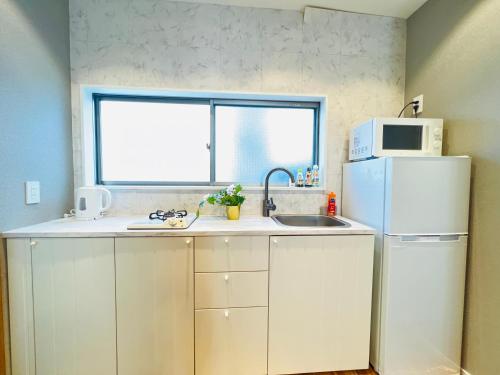 a kitchen with a white refrigerator and a microwave at Shinjuku Waseda Hostel in Tokyo