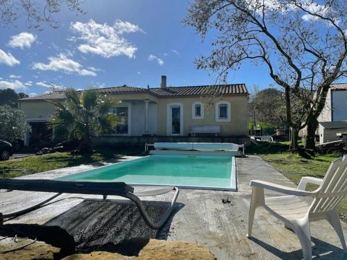 une maison avec une piscine et une chaise blanche dans l'établissement Maison avec piscine billard, à Trèbes