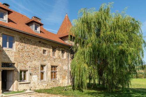 an old building with a weeping willow tree next to it at ÉCURIE DES 2 TOURS in Torchefelon