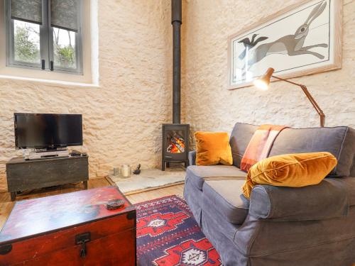 a living room with a couch and a tv and a fireplace at The Stone Barn in Loders