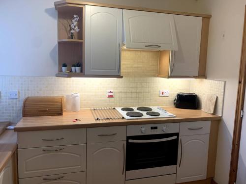 a kitchen with white cabinets and a stove top oven at Knightsridge House in Livingston