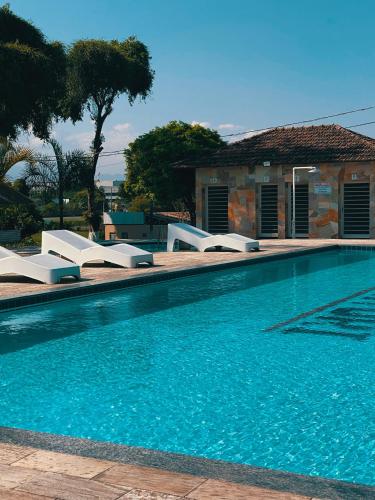 a swimming pool with white lounge chairs next to a house at O Paturi - Village Hotel Proximo Aparecida in Guaratinguetá