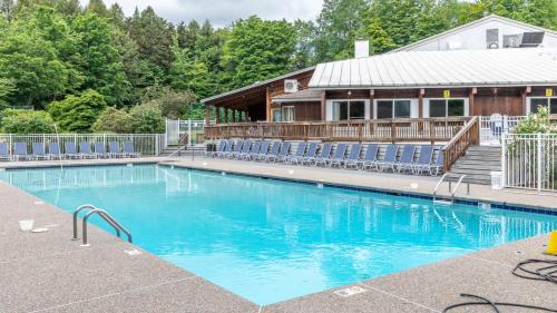 a swimming pool with blue chairs and a house at Bridges Circle condo in Warren