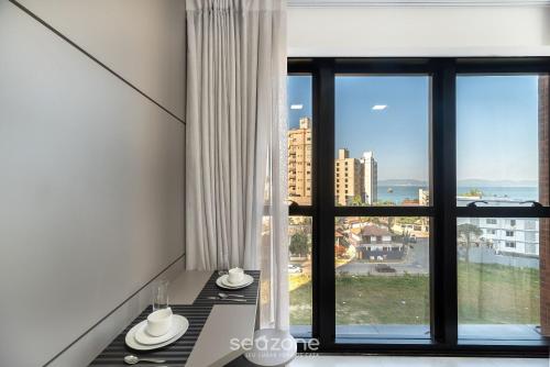 a room with a window with a view of a city at MHFA - Studios em Prédio Luxuoso com Vista Mar in Itapema