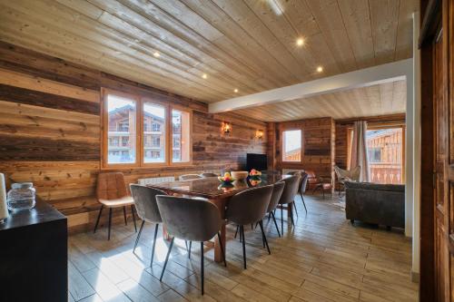 - une salle à manger avec des murs en bois, une table et des chaises dans l'établissement Chalet 1 sur la route du tour, à Huez
