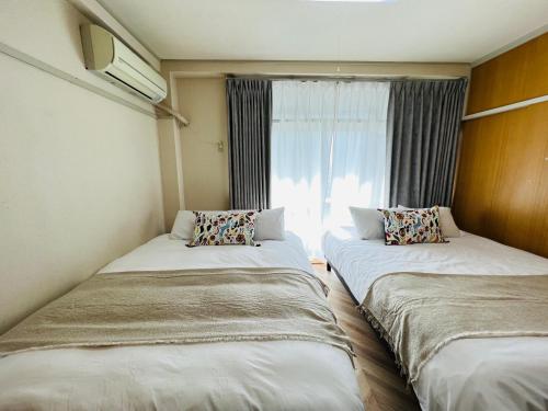 two beds in a room with a window at Shinjuku -JX house SJ0284 in Tokyo