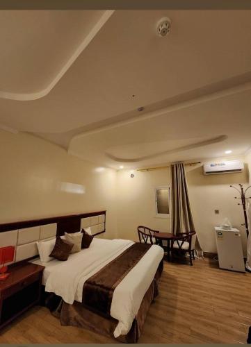 a bedroom with a large bed and a table at Fakher Yanbu Hotel in Yanbu