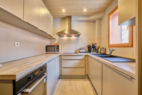 une cuisine avec un évier et un micro-ondes dans l'établissement Chalet 2 sur la route du tour, à Huez