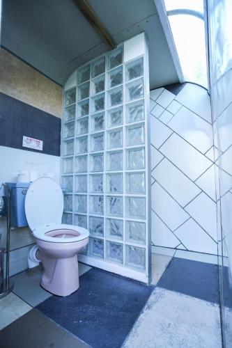 a bathroom with a toilet and a glass block wall at Little Lodge Glamping in Halesworth