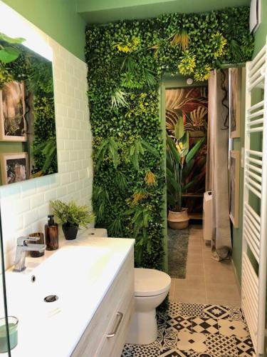 une salle de bains avec un mur vert recouvert de plantes dans l'établissement Studio Jungle Climatisé, à Brive-la-Gaillarde