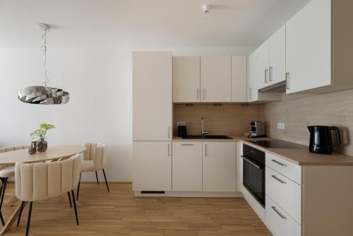 a kitchen with white cabinets and a table with chairs at COHO City Apartments mit hauseigener Tiefgarage in Vienna