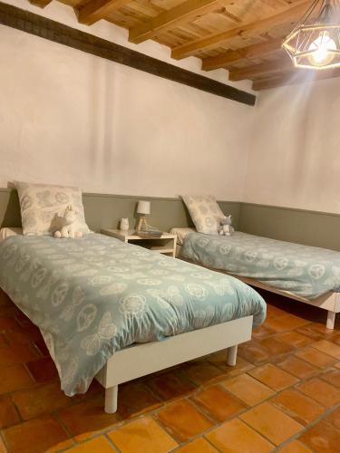 une chambre avec deux lits et une table avec une lampe dans l'établissement L Émeraude Landaise, à Allons