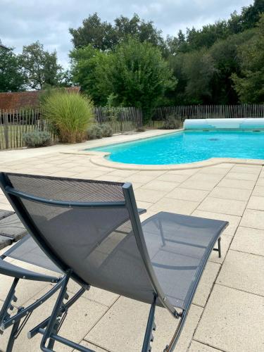 une chaise assise en face d'une piscine dans l'établissement L Émeraude Landaise, à Allons