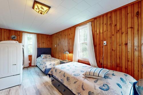 2 letti in una camera con pareti rivestite in legno di Acadia Lights Cottage a Sullivan