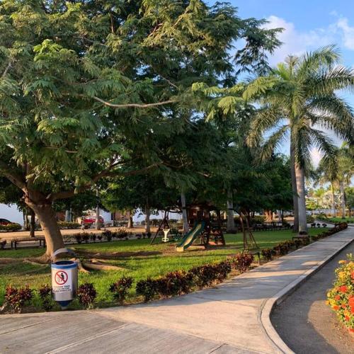 a park with palm trees and a playground with a trash can at Ejecutiva Frac privado Nueva alberca 50MB Factura in La Orilla