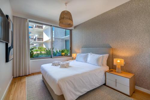 a bedroom with a large white bed and a window at Cond BAYLINE BEACH & SPA RETREAT - Linguado BY BEDZY in Armação de Pêra