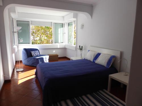 Un dormitorio con una cama azul y una ventana en PRAIA DAS AVENCAS Apt junto ao mar com estacionamento e AC, en Parede