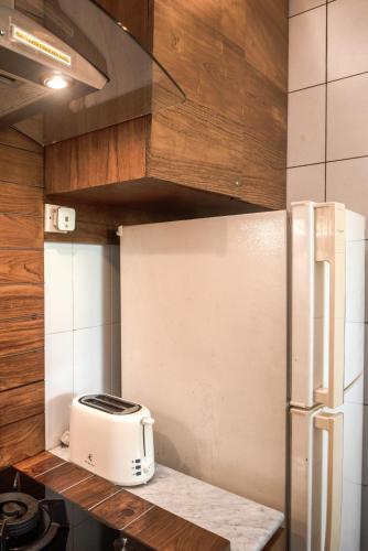 a kitchen with a toaster on a counter next to a refrigerator at Segara Beach House Villa - Kuta in Kuta