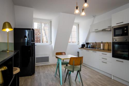 Il comprend une cuisine équipée d'une table et d'un réfrigérateur noir. dans l'établissement Hesdin Appart Holidays 2, à Hesdin