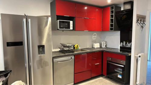 La cuisine est équipée de placards rouges et d'un réfrigérateur en acier inoxydable. dans l'établissement Appt 3Pièces centre ville Biscarrosse, à Biscarrosse