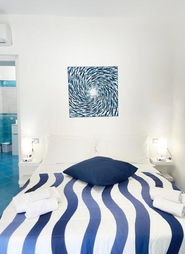 a white and blue bed with two towels on it at Chiaia Di Rose Rooms & Apartment in Ischia