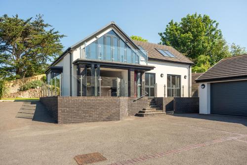 a house with glass windows and a garage at Gardd Y Llys Luxurious Family Retreat with amazing views in Llandrillo-yn-Rhôs