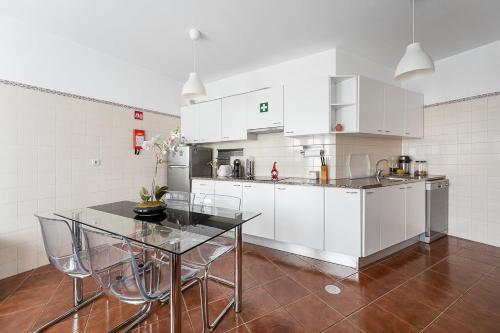 Una cocina con gabinetes blancos y una mesa de vidrio. en Relaxing time near the river, en Sebolido
