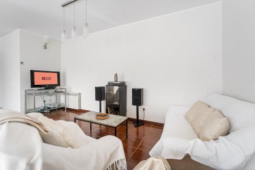 sala de estar con 2 sillas blancas y TV en Relaxing time near the river, en Sebolido