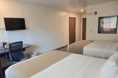 a hotel room with two beds and a desk and a tv at Microtel Inn and Suites by Wyndham Toluca in Toluca