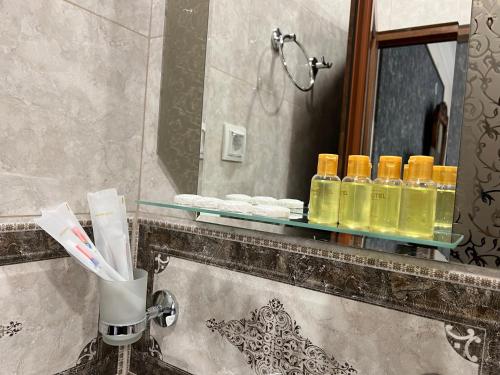 a bathroom sink with a shelf with bottles of oil at COMFORT M Guest House in Goris