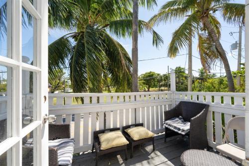 a white porch with chairs and palm trees at The Fleming Suite in Key West