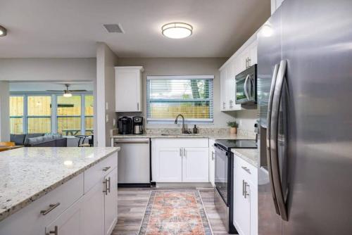 a kitchen with white cabinets and a stainless steel refrigerator at Spacious Family Oasis with Pool, BBQ, and Fire Pit in Seminole