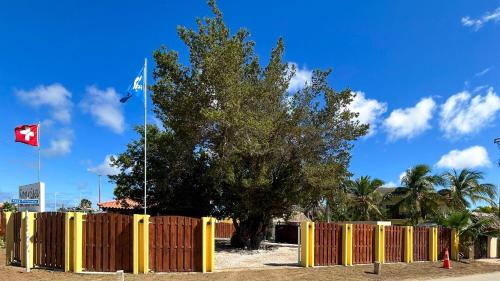 a yellow fence with a tree and a canadian flag at Sonrisa Boutique Hotel - Adults Only in Kralendijk