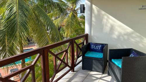 a balcony with a chair and a palm tree at Sonrisa Boutique Hotel - Adults Only in Kralendijk