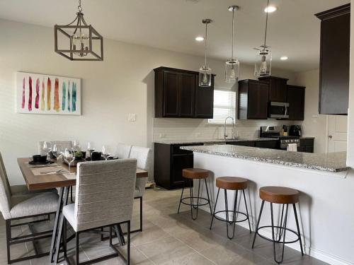 - une cuisine avec une table et quelques tabourets de bar dans l'établissement Perfect For Families House with Cozy Fireplace, à McKinney