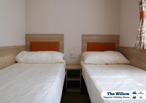 two beds in a small room with white sheets at Golden Palm Resort in Chapel Saint Leonards