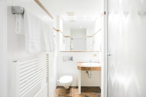 a white bathroom with a toilet and a sink at Anna 1908 in Berlin