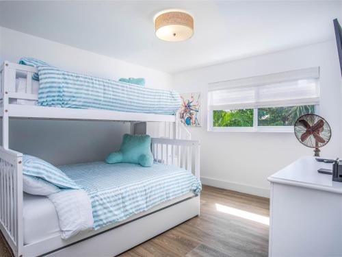 a white bedroom with a bunk bed and a window at Villa Jekjak in Cudjoe Key
