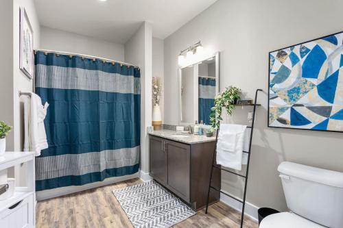 Un baño con una cortina de ducha azul y un inodoro. en Long-term Stays in Greensboro 1 BD 1 BA, en Greensboro