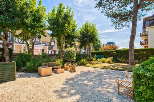 un parc avec des bancs, des arbres et des bâtiments dans l'établissement La Villa Chloé - Proche Plage - Face Au Royal - Deauville, à Deauville