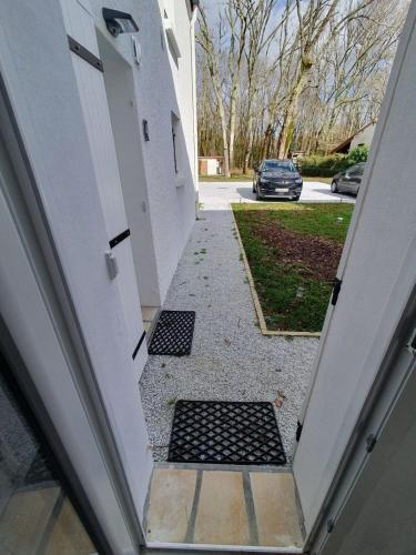an open door to a driveway with a car parked at Duplex au vert près de Royan - Appartement 4 in Médis