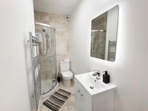 a white bathroom with a sink and a shower at Modern 4 Bed En-suite House in Leeds - Free parking in Headingley