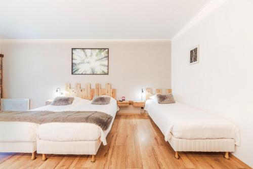 two beds in a room with white walls and wooden floors at Fleur De Neige Châtel in Châtel