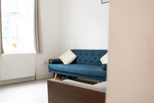 a blue couch in a living room with a window at Modern 4 Bed En-suite House in Leeds - Free parking in Headingley