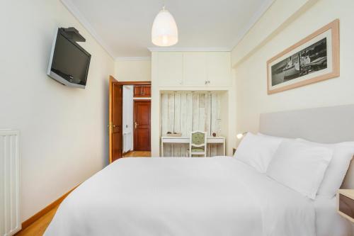 a bedroom with a white bed and a television at Cozy Penthouse in Thessaloniki